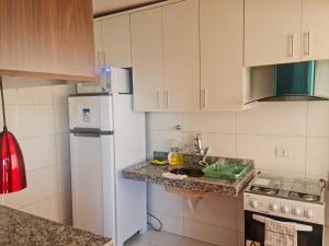 戈亚尼亚Morro Vermelho的厨房配有白色橱柜和白色冰箱。