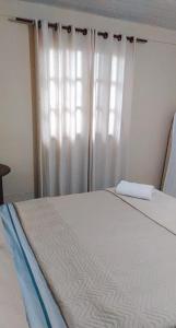 特雷索波利斯Hospedagem Doce Lar - Casa Girassol的一间卧室配有床和白色窗帘的窗户