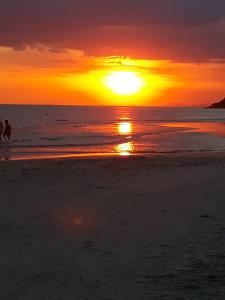 圣保罗CONDOMÍNIO ILHAS DO JUQUEHY的两人在日落时分在海滩上散步