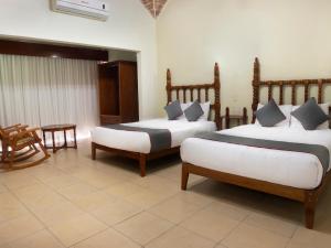 韦拉克鲁斯Collection O Hotel Mocambo, Boca del Río的一间卧室配有两张床和一张桌子及椅子