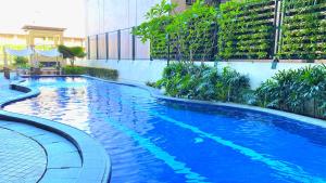 马尼拉One Pacific Place Serviced Residences的一座大型蓝色游泳池,位于大楼旁边