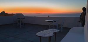 伊亚Aethrio Sunset Village - Oia的阳台享有日落美景,配有桌椅。