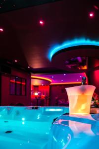 图卢兹L'Insolite Spa Privatif ''Suite Luxueuse-Jacuzzi"的一间设有紫色和蓝色灯光浴缸的客房