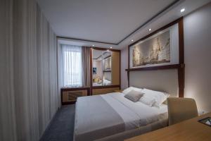 贝尔格莱德Putnik Inn Belgrade的一间卧室配有一张床、一张桌子和一个窗户。