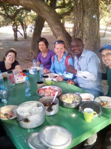 NgomaNaumba Camp and Campsite的一群人坐在桌子旁吃着食物