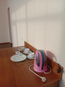 喀山Azalya Hotel的一张桌子,上面有粉红色的电视,盘子和杯子