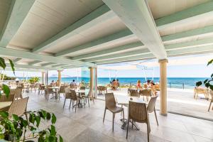 圣特奥多罗六边形酒店的海滩上的餐厅,配有桌椅