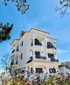 大叻Bạch Trà Villa的带阳台和树木的白色建筑