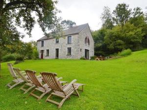 希迈Quaint Holiday Home in Robechies amid Meadows的两把椅子坐在房子前面的草上