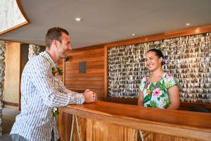 波拉波拉Le Bora Bora by Pearl Resorts的男人和女人在酒吧摇手