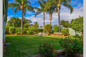 伊丘卡Wandew - Echuca Holiday Homes的棕榈树庭院和绿色草坪