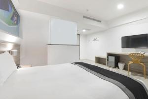 台中市传思文旅的一间白色卧室,配有一张大床和一台电视