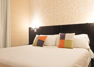 布宜诺斯艾利斯里贝拉苏尔酒店的卧室配有白色的床和2个色彩缤纷的枕头