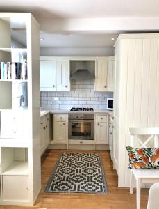 布莱顿霍夫Charming Cottage & Garden - central Brighton!的厨房配有白色橱柜和地毯。
