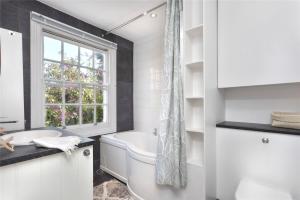 布莱顿霍夫Charming Cottage & Garden - central Brighton!的白色的浴室设有浴缸和窗户。