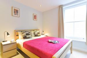 伦敦Shoreditch Vibe Apartments的一间卧室配有一张带红色毯子的大床