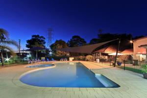 Emu Plains比格斯尼皮恩河假日公园的一座游泳池,晚上与大楼相连