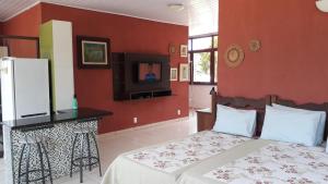 卡瓦坎特Tapuio Park Hotel的一间带红色墙壁、一张床和电视的卧室