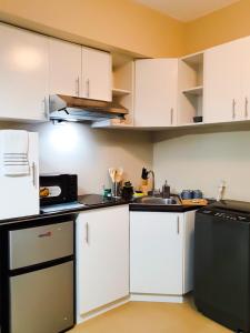 伊洛伊洛Zen Living Condo at Avida Atria Tower 2的厨房配有白色橱柜和黑色用具