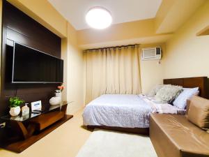伊洛伊洛Zen Living Condo at Avida Atria Tower 2的一间卧室配有一张床和一台平面电视