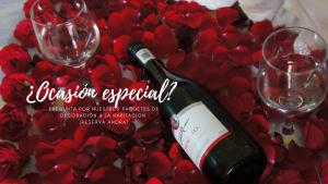 圣胡安特奥蒂瓦坎Posada y Spa Jade Teotihuacan的一瓶葡萄酒和两杯红玫瑰花桌子上的酒