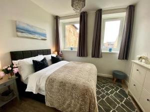 林利斯戈Central Apartment Linlithgow的一间卧室设有一张床和两个窗户。