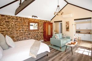 麦克拉伦谷Settlers Cottage的一间卧室设有砖墙、一张床和一张沙发