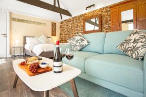 麦克拉伦谷Settlers Cottage的客厅配有蓝色的沙发和一瓶葡萄酒