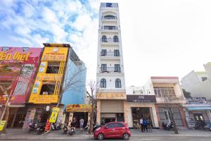 绥和市Rivera Tuy Hòa Hotel的一群在城市街道上用一辆红色汽车建造的建筑物