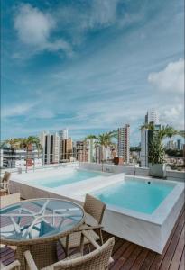 若昂佩索阿Manaíra Apart Hotel的屋顶上带椅子和桌子的游泳池