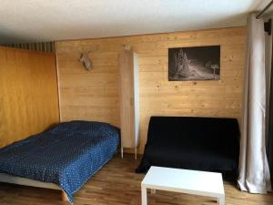 圣让多尔普Le Relai S34 - Grand et lumineux studio avec coin montagne 4-6 pers avec WIFI, 50m des pistes, grand balcon exposé SUD, DRAPS NON COMPRIS的一间卧室设有一张床和木墙