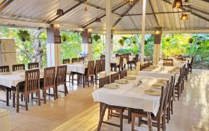 萨三吉尔Hotel Anil Farmhouse Gir Jungle Resort的用餐室配有白色桌椅和桌子。