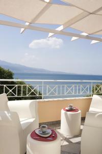 纳弗帕克托斯阿卡缇酒店的阳台配有白色椅子,享有海景。