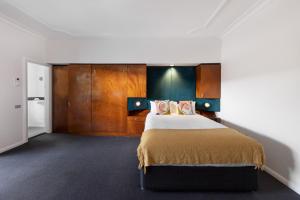悉尼悉尼丽景阁酒店的一间卧室配有一张大床和木制橱柜。