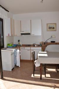洛雷茨卡APP Rojko的厨房配有白色橱柜、桌子和桌椅