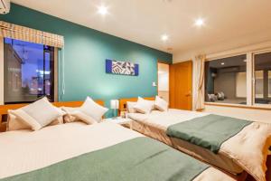 札幌THE WORLDWIDE HOUSE的卧室设有两张床铺和绿色的墙壁