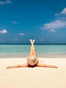 弗里德胡岛屿度假宾馆的戴着帽子躺在沙滩上的女人