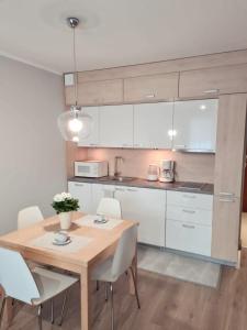 斯维诺乌伊希切Apartament Baltic的厨房配有木桌和白色橱柜。