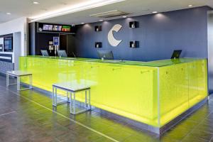 常滑市中央国际机场康福特茵酒店的大堂的黄色柜台,配有两张桌子