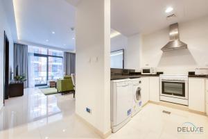 迪拜Sleek 1BR Apartment at Celestia Dubai South by Deluxe Holiday Homes的白色的厨房配有洗衣机和烘干机