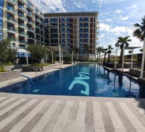迪拜Sleek 1BR Apartment at Celestia Dubai South by Deluxe Holiday Homes的大楼前的大型游泳池