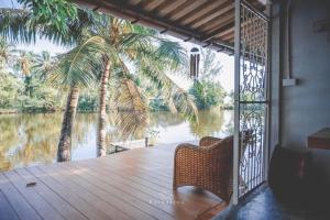 Takua PaThipwararom homestay的享有河流和棕榈树景致的门廊
