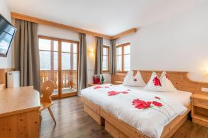 圣洛伦佐-迪塞巴托琳娜霍夫酒店的一间卧室配有一张红色鲜花的大床