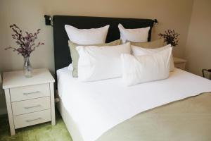 北哈夫洛克Apartment on St Georges的一张带白色枕头的床和床头柜上的花瓶