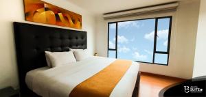 波哥大莫德利尔广场公寓式酒店的一间卧室设有一张大床和大窗户