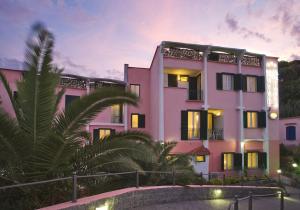 伊斯基亚Fortuna Beach - Seaside Hotel的前面有棕榈树的粉红色建筑