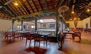 AlleppeyTreebo Tryst Travancore Palace Cherthala的一个带桌椅的用餐室和一个游泳池