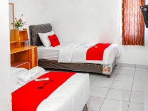 曼诺瓦里RedDoorz near Reremi Pemancar Manokwari的小客房内的两张床,配有红色和白色的床单