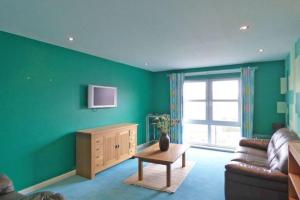 阿伯丁Comfortable, self contained 2 double beds town apartment near Pittodrie Stadium的客厅设有绿色的墙壁、一张沙发和一张桌子