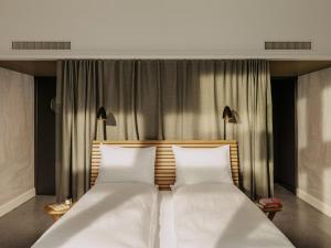 巴塞尔Boutique & Design Hotel Volkshaus Basel的一间卧室配有2张白色的床和2盏灯。